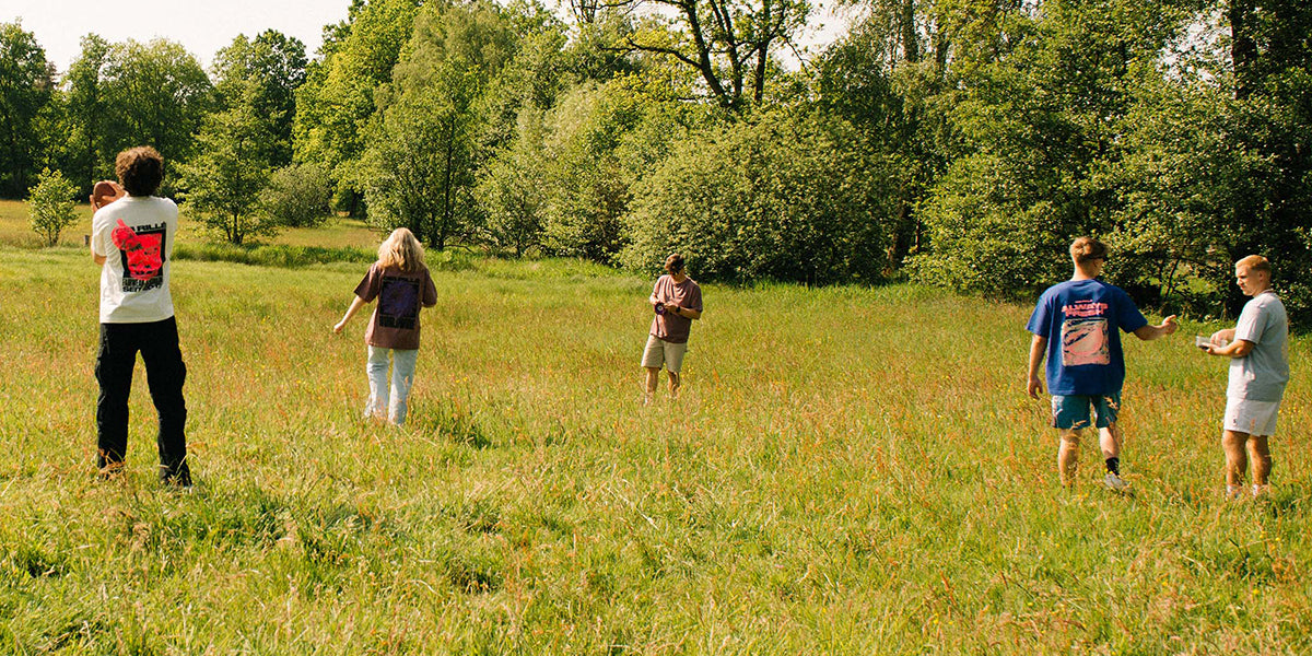 Gib Rillé Outdoor-Shooting auf einer Wiese, mit Models, die nachhaltige Mode in der Natur tragen, umgeben von grünen Wiesen und einer entspannten, natürlichen Atmosphäre.