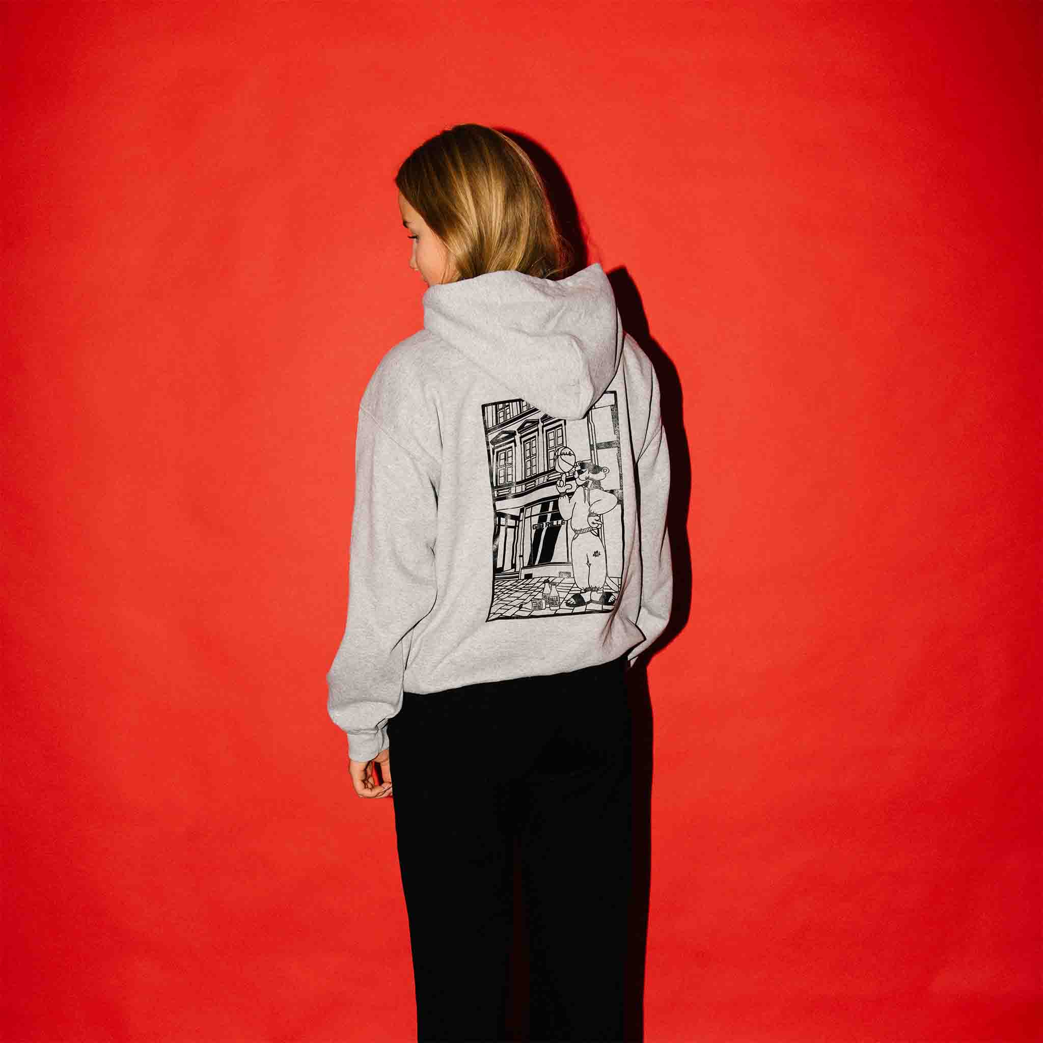 Model trägt den grauen Panther Hoodie von Gib Rillé mit auffälligem Backprint. Die nachhaltige Mode wird im Streetstyle-Look präsentiert.