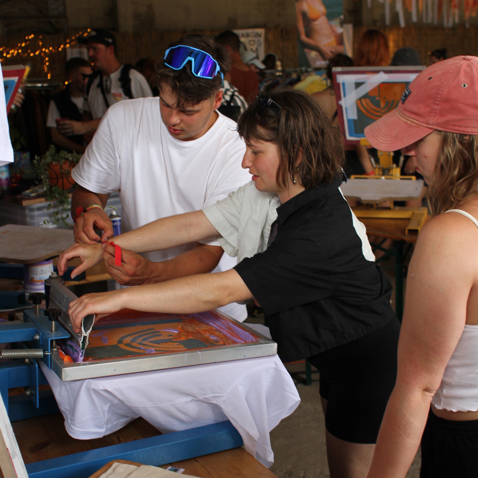 Siebdrucker zeigt Siebdruck Workshop Teilnehmer wie man siebdruckt 